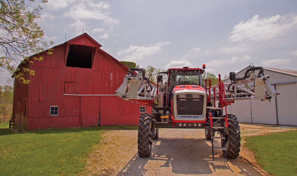 Apache Sprayer in front of red barn