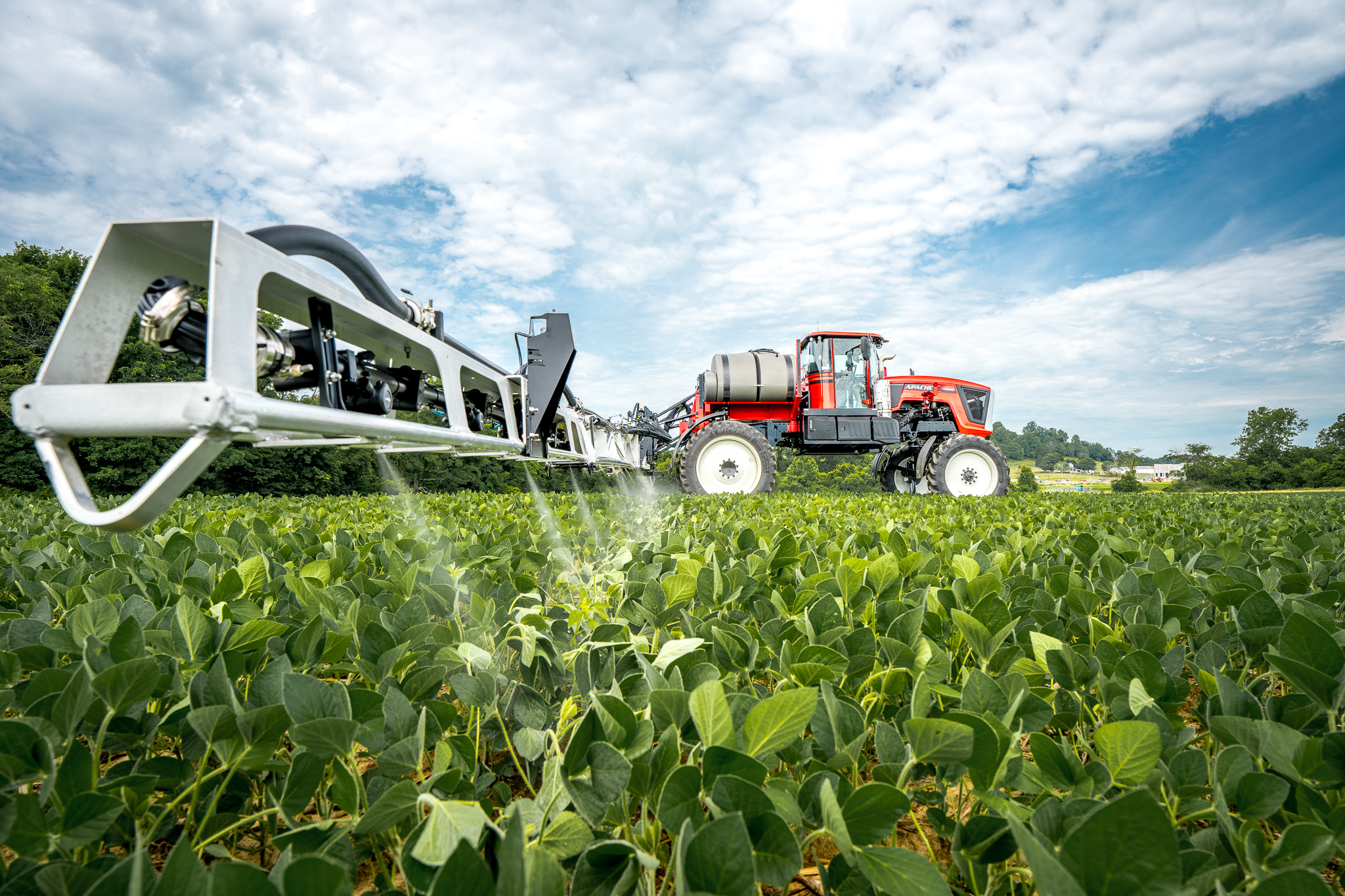 apache sprayer with boom extended. Spraying in field with tip of boom close to camera